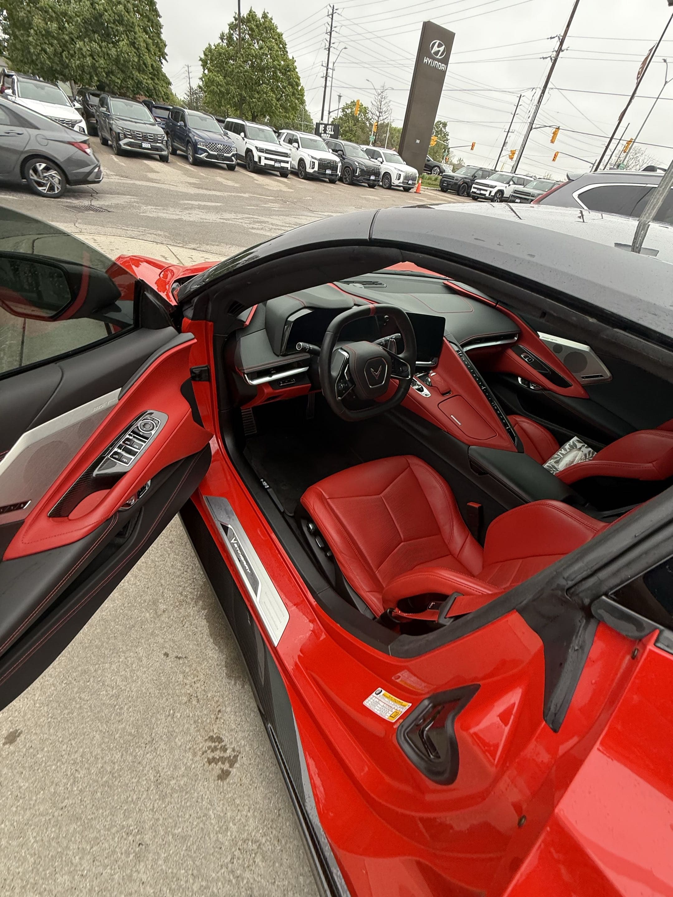 Red sports car interior with red leather seats and black dashboard in a dealership lot.
